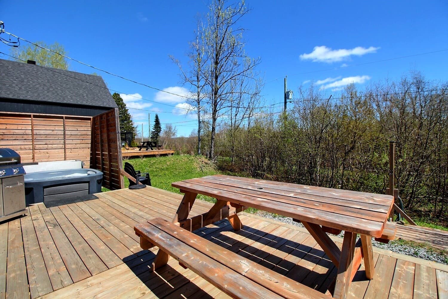 Grande terrasse de bois, spa, BBQ et table du chalet Monsieur Ferréol