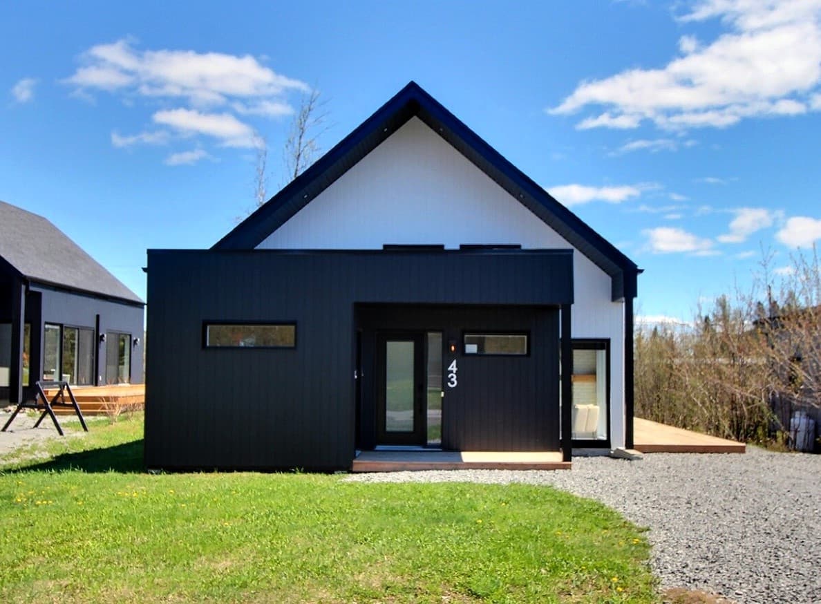 Entrée du chalet numéro 43, siding noir et porte vitrée à Saint-Ferréol-les-Neiges